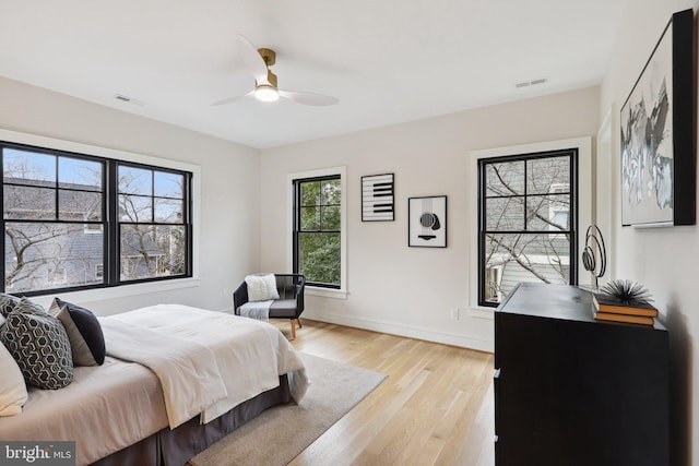 bedroom with a ceiling fan, baseboards, visible vents, and light wood finished floors