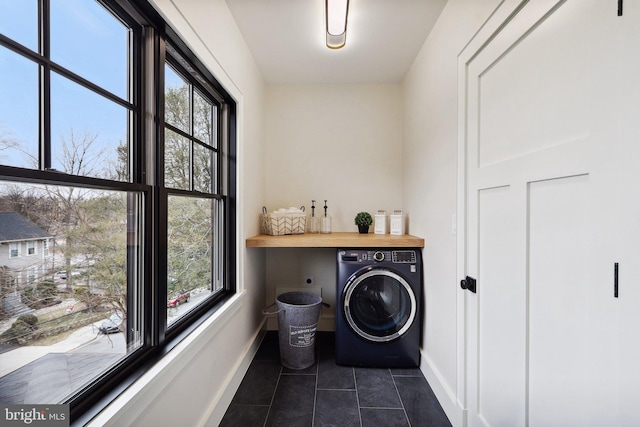 clothes washing area with laundry area, dark tile patterned floors, washer / dryer, and baseboards