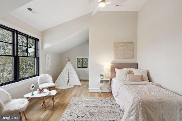 bedroom featuring light wood-style floors, baseboards, visible vents, and vaulted ceiling