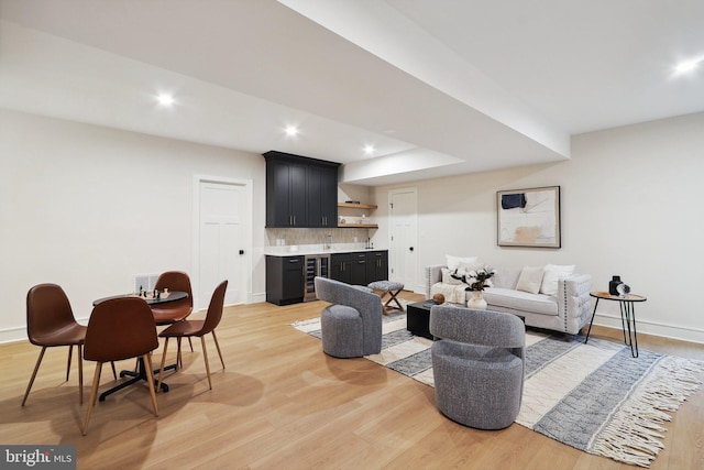 living area with light wood-style floors, recessed lighting, indoor wet bar, and baseboards