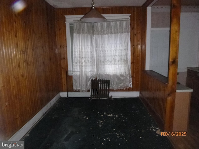 unfurnished dining area with radiator and wood walls