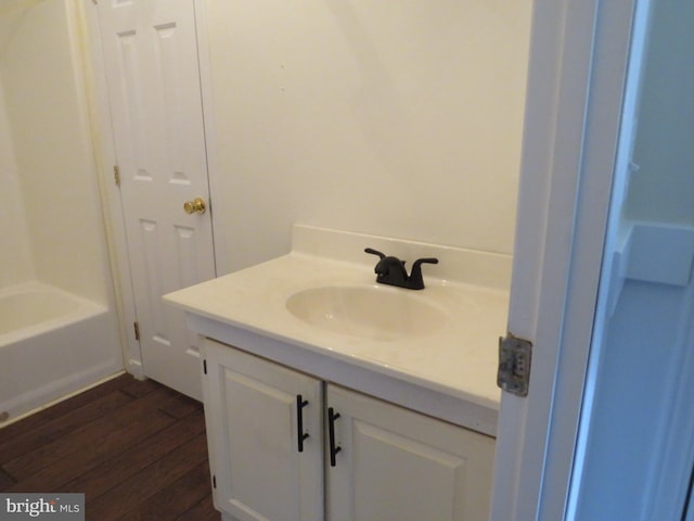 bathroom with hardwood / wood-style flooring, vanity, and a tub