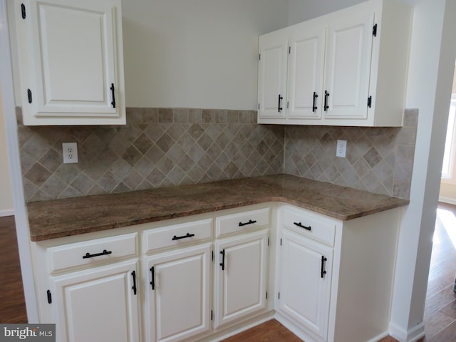 kitchen with tasteful backsplash, white cabinetry, and dark stone countertops