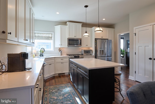 kitchen with sink, a center island, appliances with stainless steel finishes, a kitchen breakfast bar, and pendant lighting