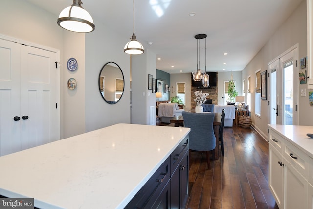 kitchen featuring pendant lighting, dark wood-type flooring, white cabinetry, a fireplace, and a kitchen island