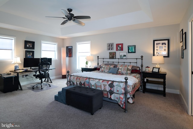 carpeted bedroom featuring ceiling fan and a tray ceiling