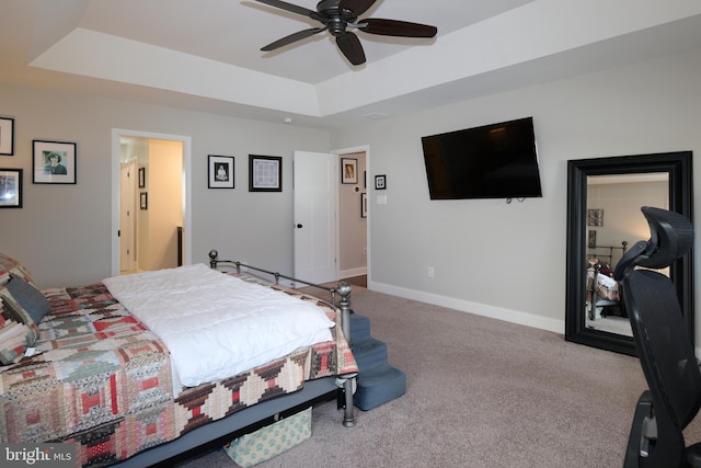 carpeted bedroom featuring a tray ceiling and ceiling fan