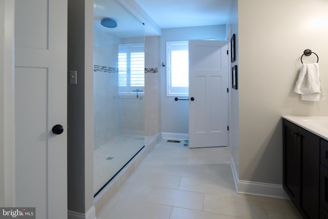 bathroom featuring tiled shower, vanity, and tile patterned flooring