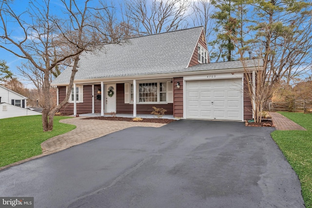 view of front of property featuring driveway, roof with shingles, an attached garage, and a front yard