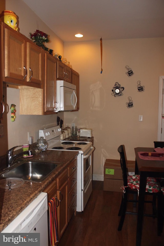 kitchen with dark hardwood / wood-style flooring, sink, dark stone countertops, and white appliances