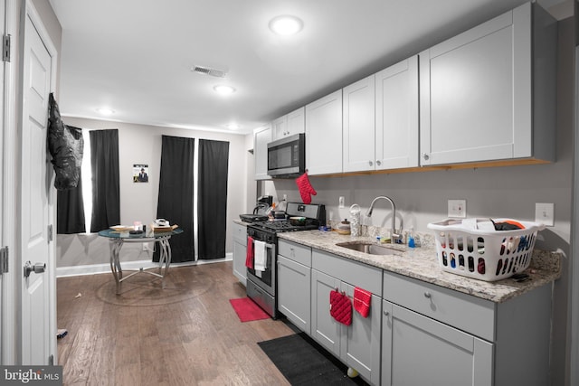 kitchen featuring sink, gray cabinetry, stainless steel appliances, light stone counters, and light wood-type flooring