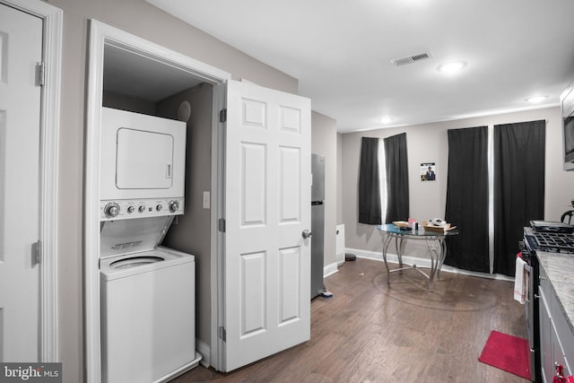 clothes washing area with dark hardwood / wood-style floors and stacked washing maching and dryer