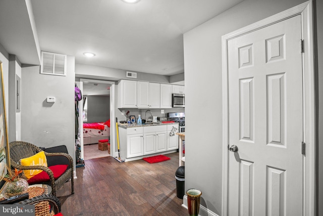 kitchen featuring dark wood-type flooring, sink, light stone counters, stainless steel appliances, and white cabinets