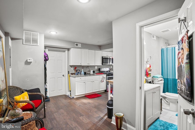 kitchen featuring stainless steel appliances, sink, white cabinets, and dark hardwood / wood-style flooring