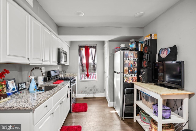 kitchen featuring sink, appliances with stainless steel finishes, white cabinetry, dark hardwood / wood-style floors, and light stone countertops