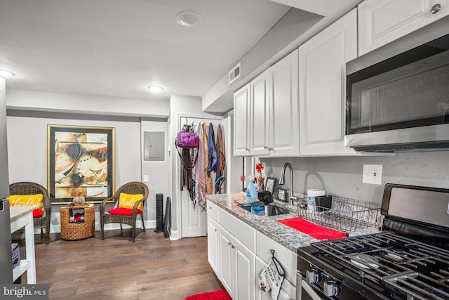 kitchen with light stone counters, sink, gas range oven, and white cabinets