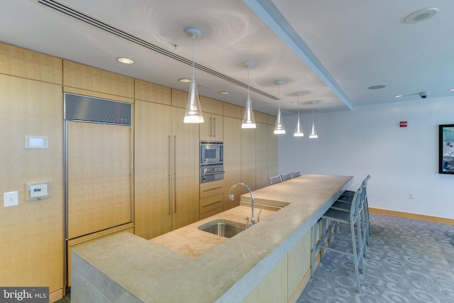 kitchen featuring sink, built in appliances, a center island with sink, hanging light fixtures, and light brown cabinets