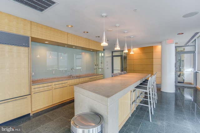 kitchen featuring a kitchen island, light brown cabinetry, decorative light fixtures, sink, and paneled fridge