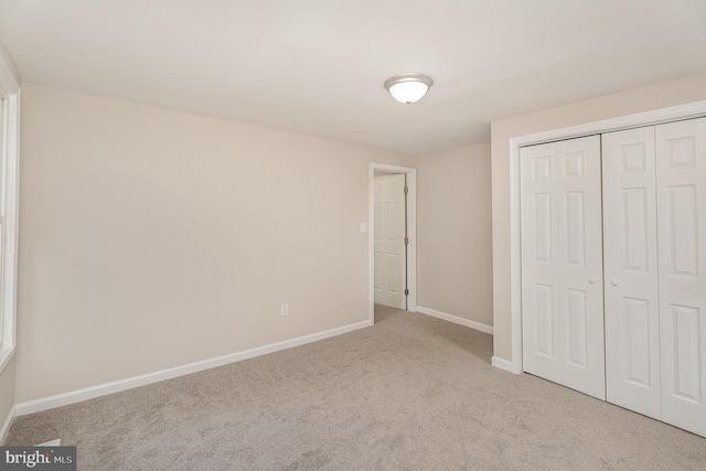 unfurnished bedroom featuring light colored carpet and a closet