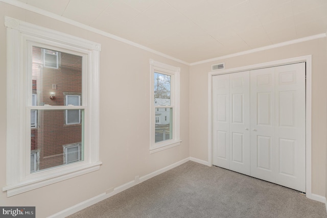 unfurnished bedroom featuring light colored carpet, ornamental molding, and a closet