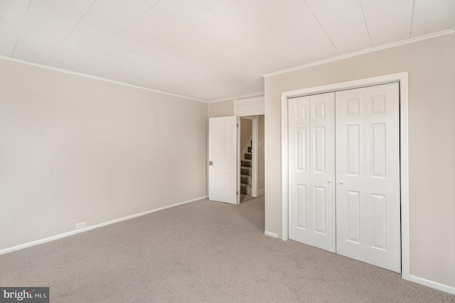 unfurnished bedroom with crown molding, carpet floors, and a closet