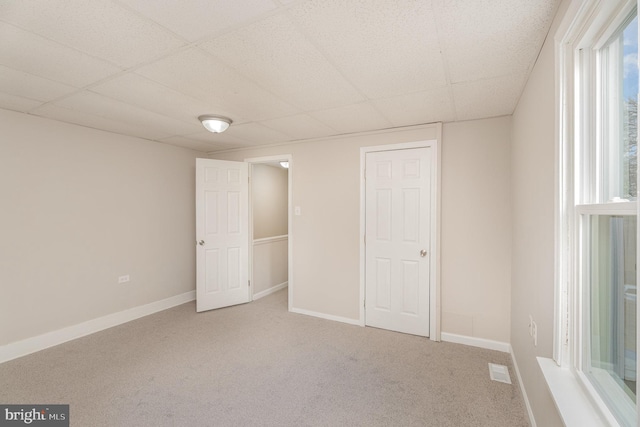 unfurnished bedroom with a paneled ceiling and carpet