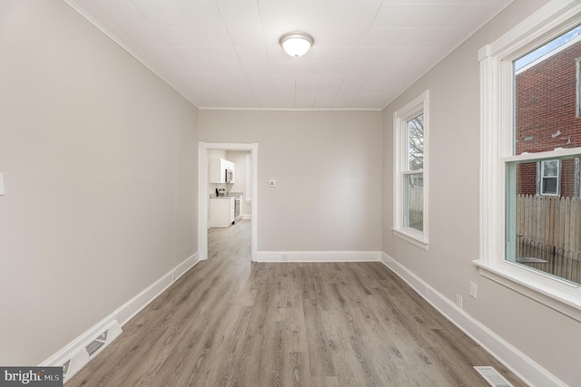 empty room with ornamental molding and light hardwood / wood-style floors