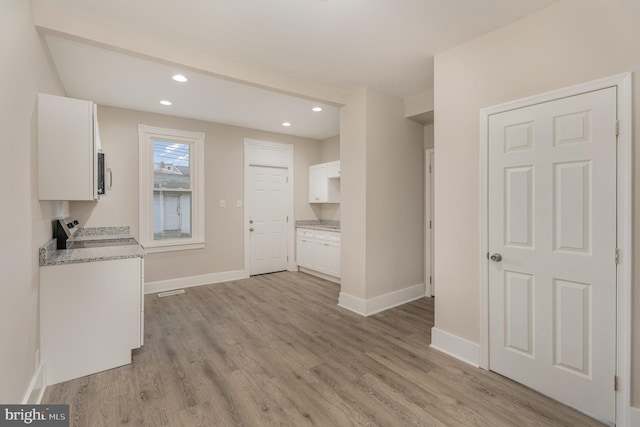 kitchen featuring white cabinetry, light stone countertops, range, and light wood-type flooring