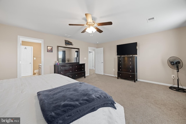 bedroom with ceiling fan, light colored carpet, and ensuite bath