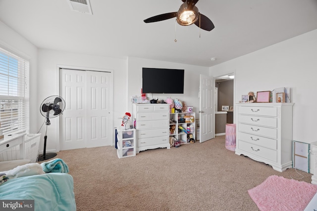 bedroom with ceiling fan, a closet, and light carpet