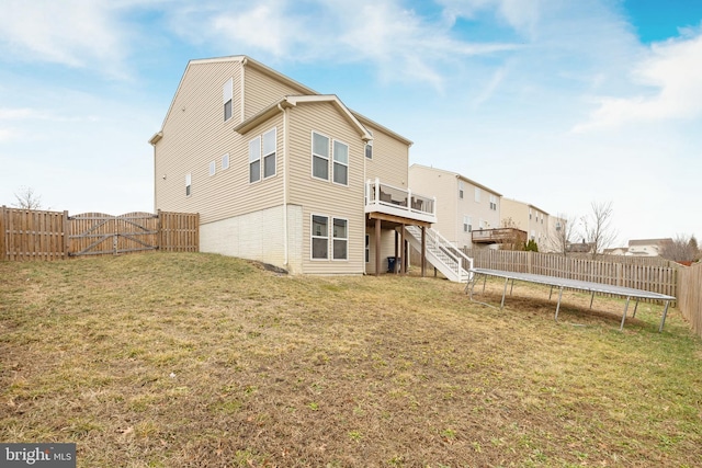 rear view of house with a deck, a trampoline, and a lawn