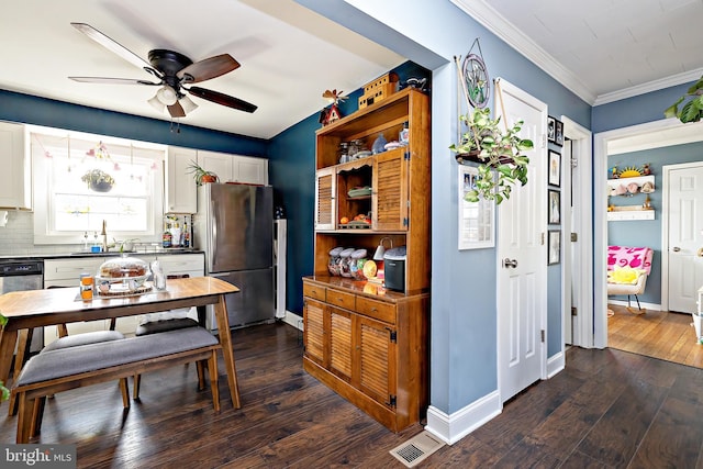 kitchen with crown molding, dark wood-type flooring, stainless steel appliances, tasteful backsplash, and white cabinets