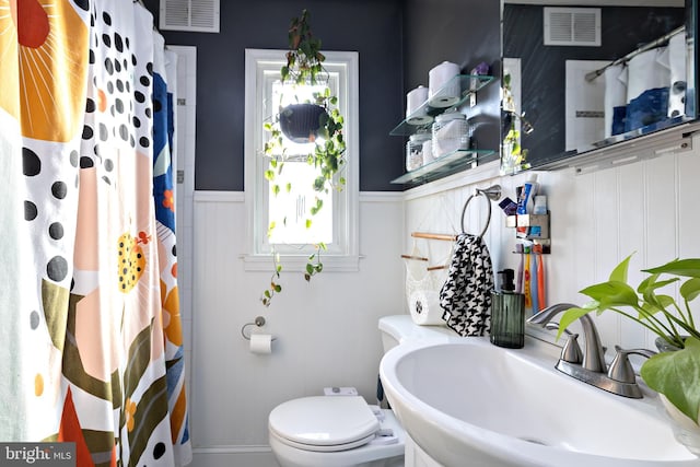 bathroom featuring walk in shower, toilet, and sink