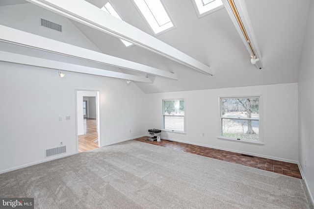 spare room featuring a skylight, carpet, visible vents, and beamed ceiling