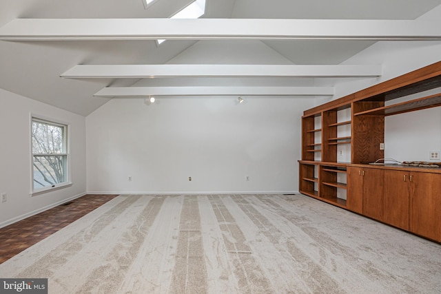 empty room with lofted ceiling with beams, carpet flooring, and baseboards