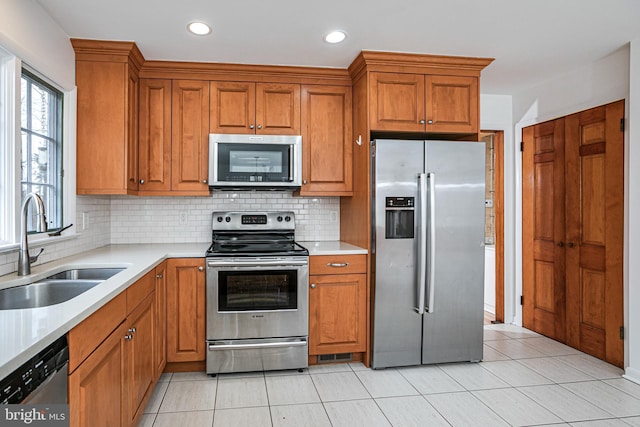 kitchen with appliances with stainless steel finishes, light countertops, and a sink