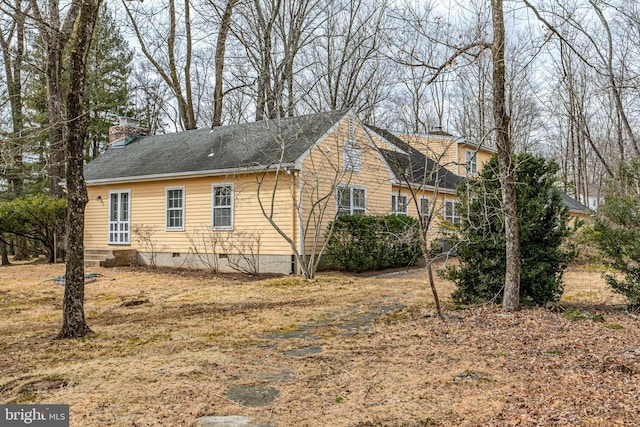 view of side of home featuring crawl space and a shingled roof