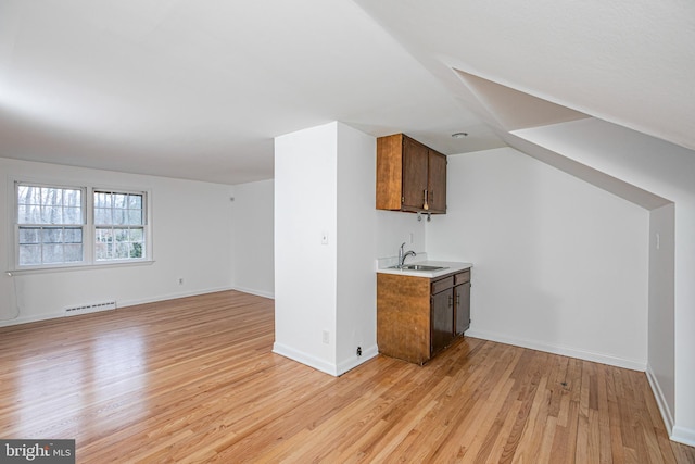 bar with light wood-type flooring, a sink, visible vents, and baseboards