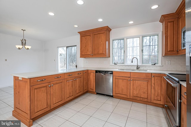 kitchen featuring stainless steel appliances, a peninsula, a sink, and light countertops