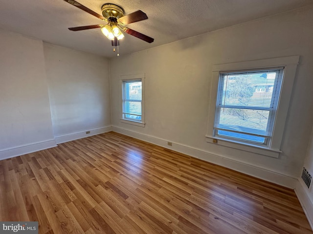 empty room with hardwood / wood-style flooring, ceiling fan, and a textured ceiling