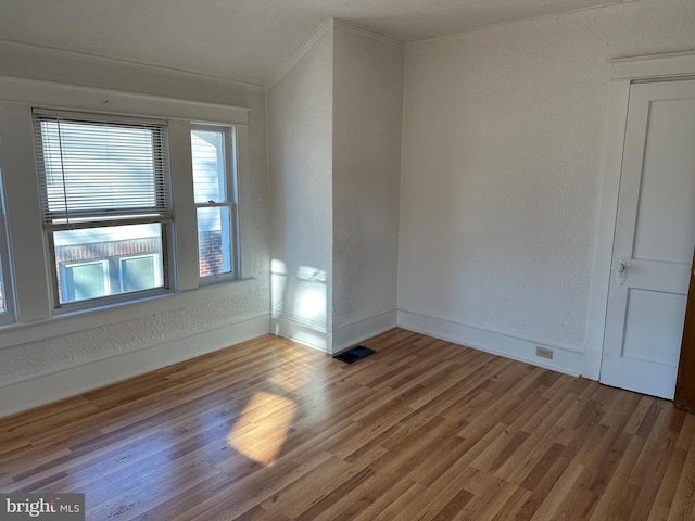 spare room featuring crown molding and wood-type flooring