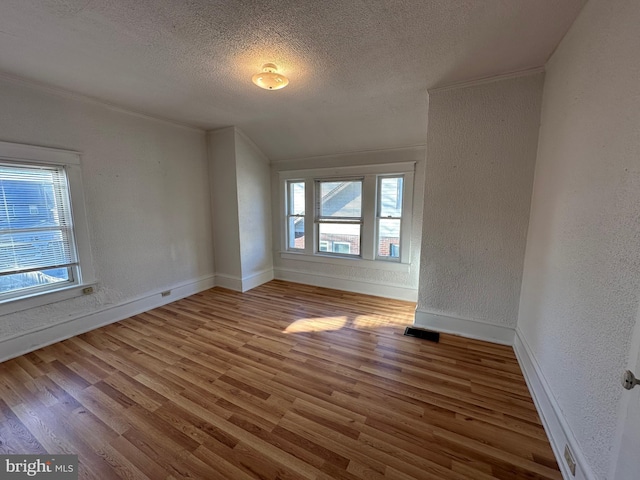 unfurnished room with hardwood / wood-style flooring, ornamental molding, and a textured ceiling