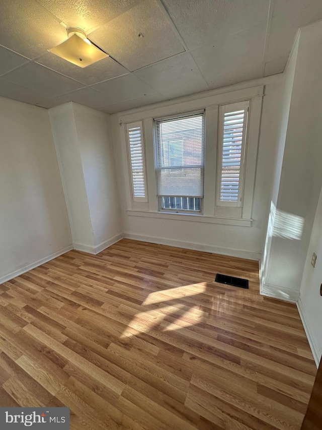 unfurnished room featuring a drop ceiling and wood-type flooring