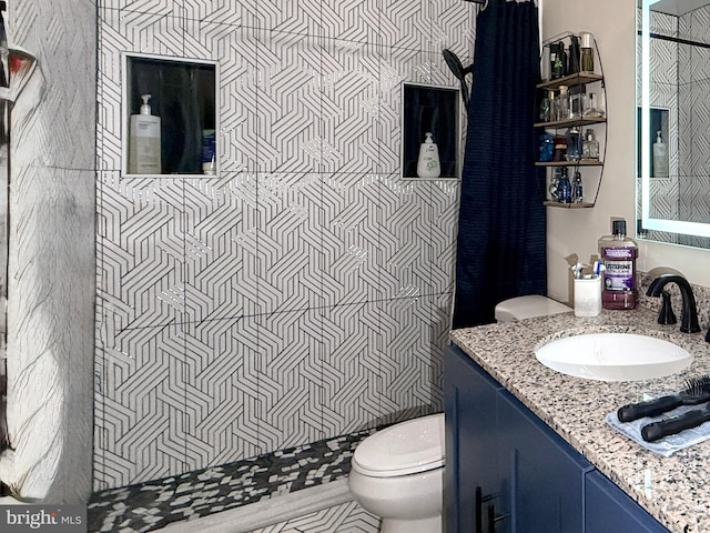 bathroom featuring vanity, toilet, and a tile shower