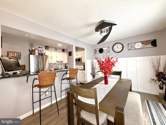 dining space featuring wood-type flooring and a textured ceiling