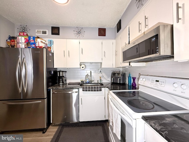 kitchen featuring sink, appliances with stainless steel finishes, backsplash, a textured ceiling, and white cabinets