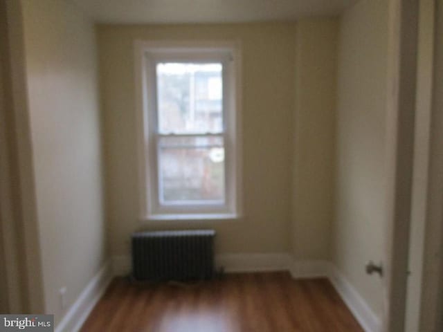 empty room with hardwood / wood-style flooring and radiator