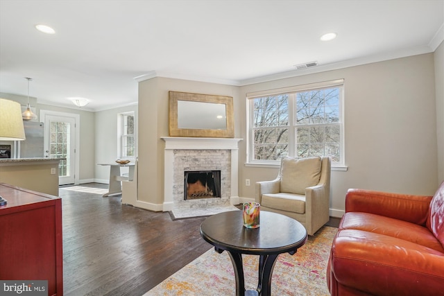 living area featuring visible vents, wood finished floors, a fireplace, crown molding, and baseboards