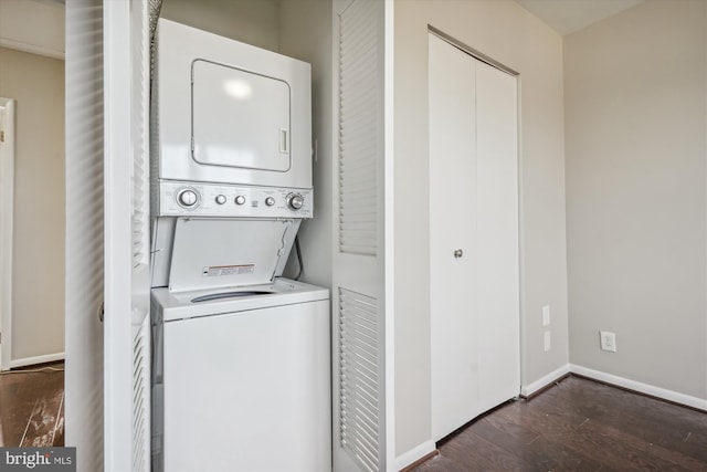 washroom with laundry area, wood finished floors, baseboards, and stacked washer and dryer