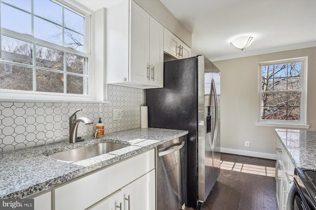 kitchen with white cabinetry, ornamental molding, a sink, stainless steel dishwasher, and backsplash